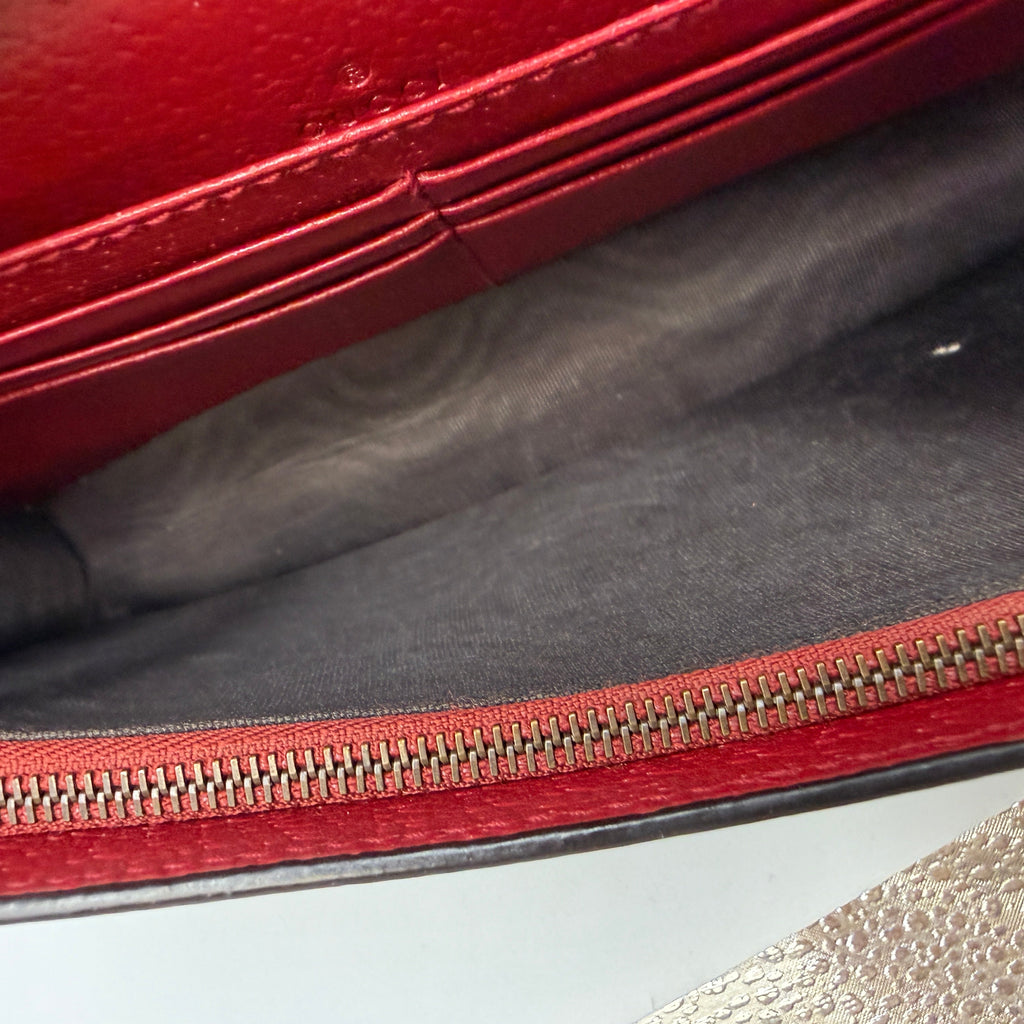 Close-up of a red leather bag with a zipper on a gray surface