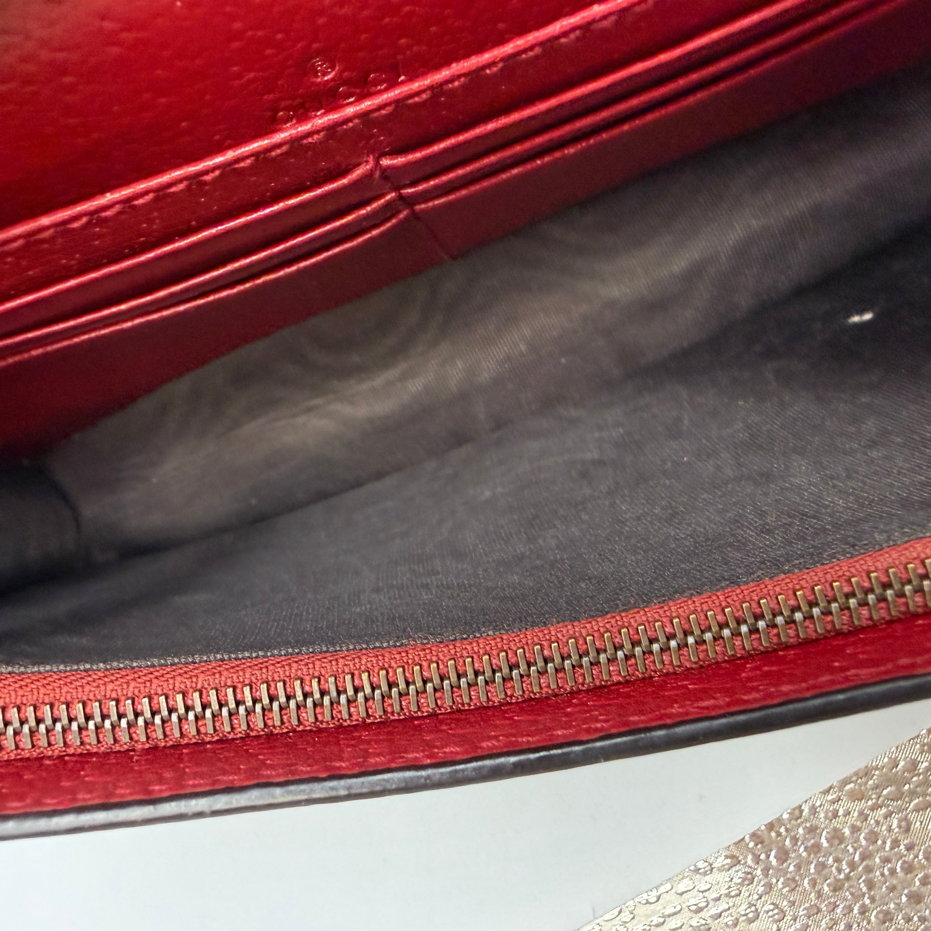 Close-up of a red leather bag with a zipper on a gray surface