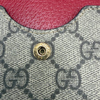 Close-up of a Gucci handbag with a gold button and red leather patch.