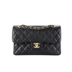 Black quilted handbag with gold chain and clasp on a white background