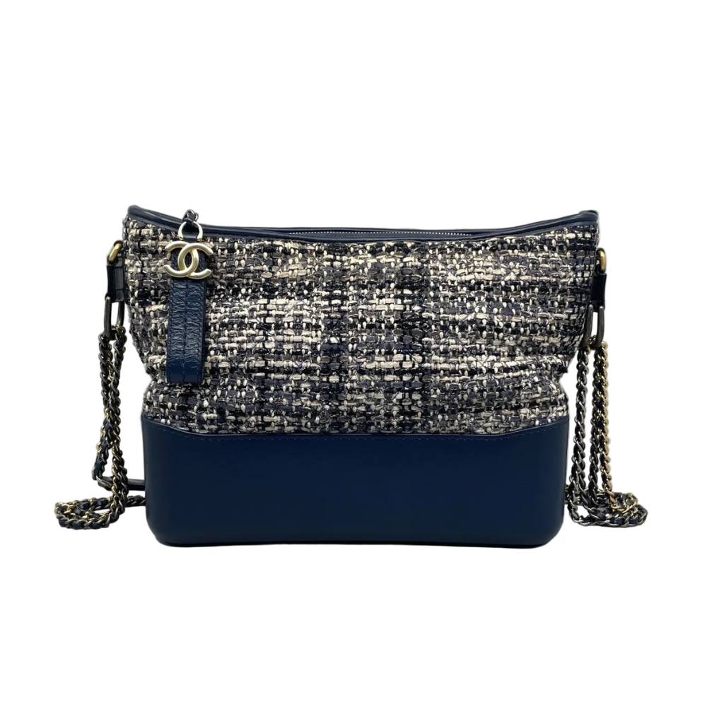Front view of a Chanel Small Gabrielle Hobo bag featuring navy quilted tweed, a structured navy blue calfskin base, and a multi-metal chain strap in gold, silver, and ruthenium.