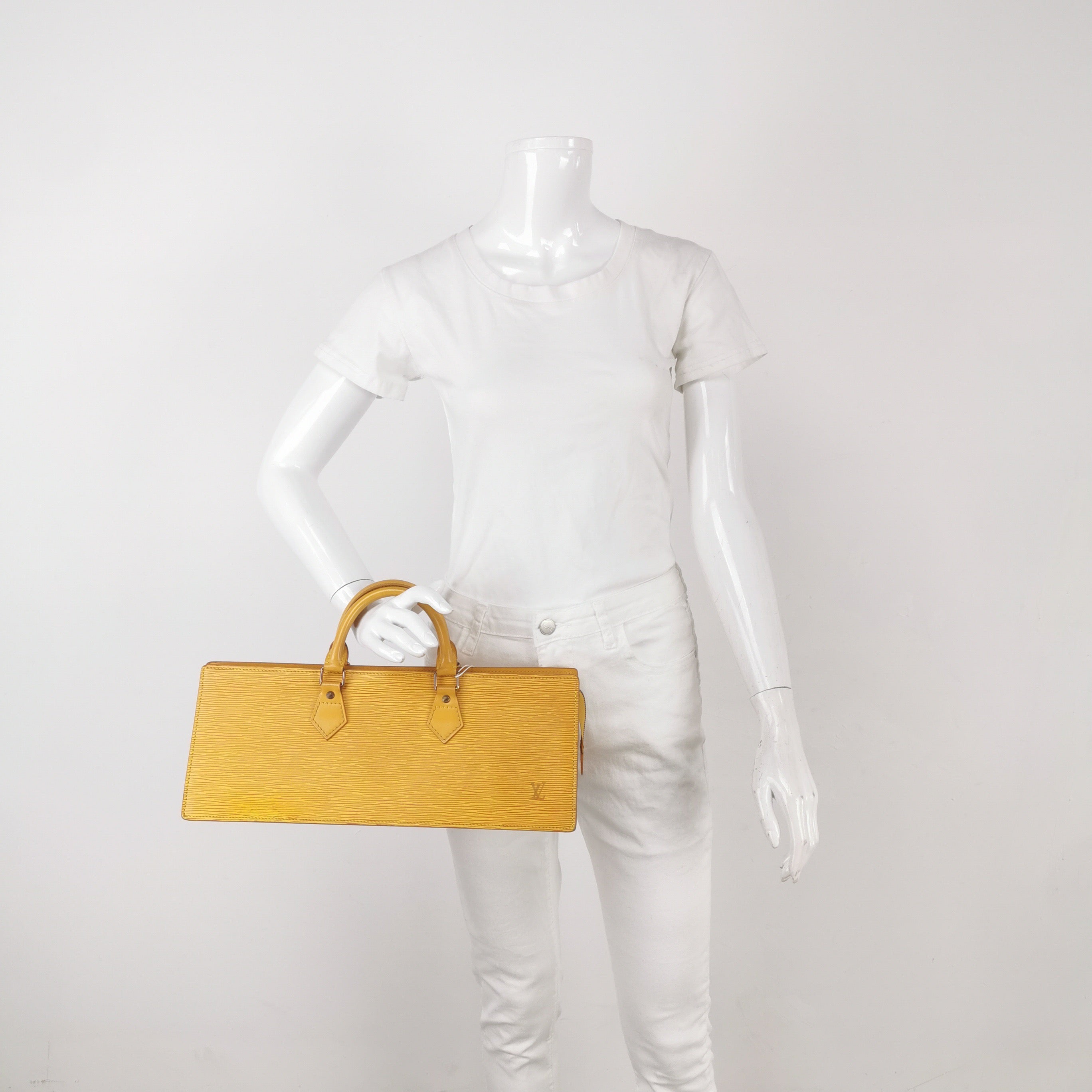 Mannequin holding a yellow LV vintage handbag with epi leather and lv logo 