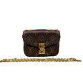 Front view of a miniature Louis Vuitton Micro Metis bag in Monogram canvas, featuring a gold-tone S-lock, Vachetta leather handle, and a removable gold chain strap on a white background.