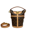 Front view of a Louis Vuitton Monogram Canvas Duffle bucket bag featuring a gold-tone S-lock trunk closure, Vachetta leather handle, and a matching detachable crossbody strap on a white background.