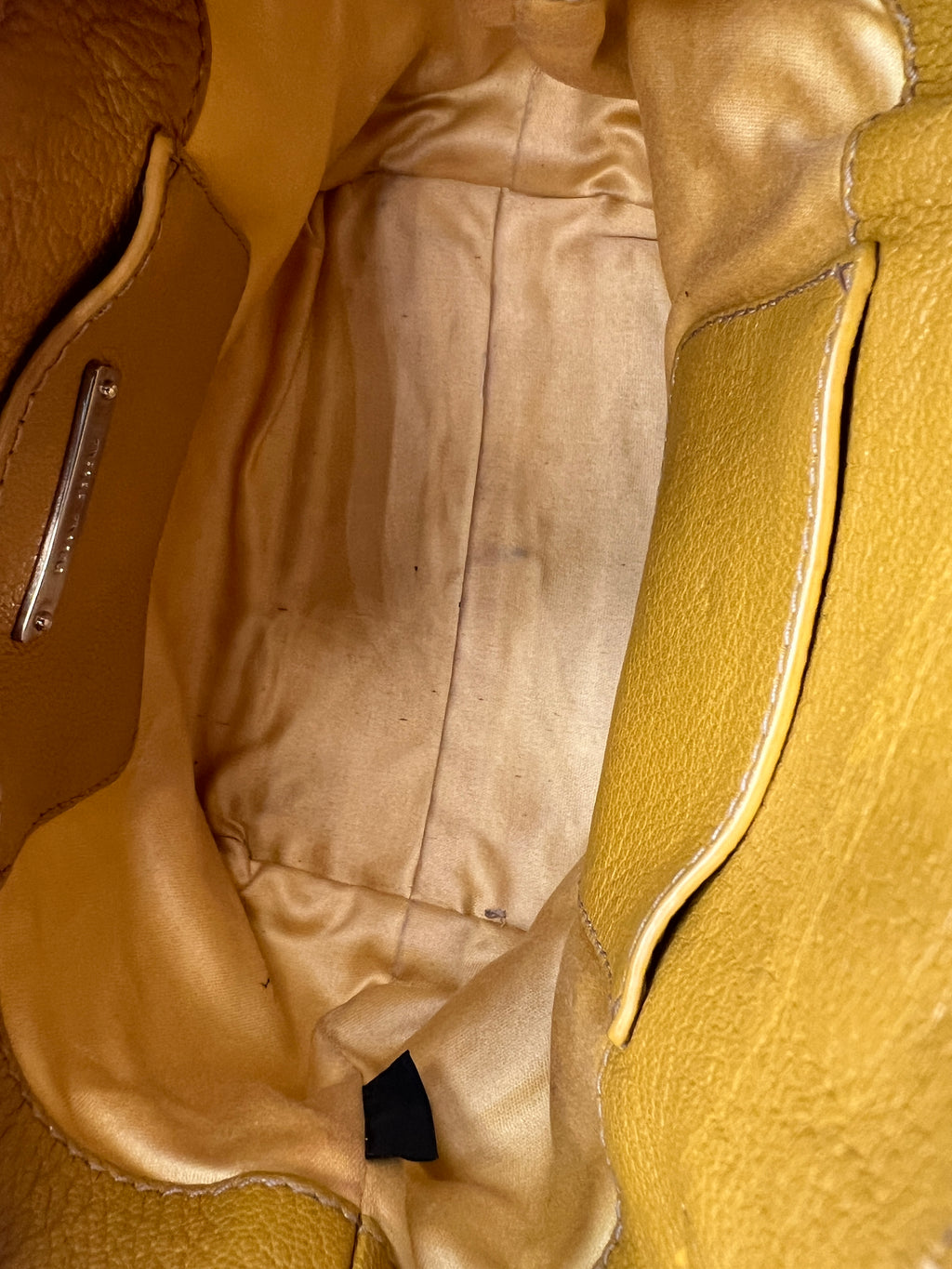 Close-up of a brown leather bag with visible stitching and a zipper. MIUMIU-HANDBAG