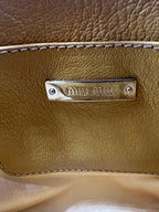 Close-up of a brown leather bag with a visible brand logo. MIUMIU-CROSSBODYBAG