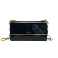Front view of a Prada flap shoulder bag in shiny black Spazzolato patent leather, featuring a gold-tone Prada logo and a decorative gold-tone chain strap against a white background.