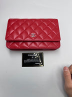 Front view of a Chanel Classic Wallet on Chain in red quilted lambskin leather with silver CC logo and authenticity card.