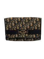 Front view of a vintage Christian Dior Trotter Oblique canvas clutch bag with navy pattern and central gold CD logo clasp.