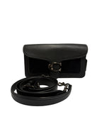 A black leather shoulder bag with a textured flap and a large silver-tone buckle, shown with its matching black leather strap coiled in front on a light gray background.