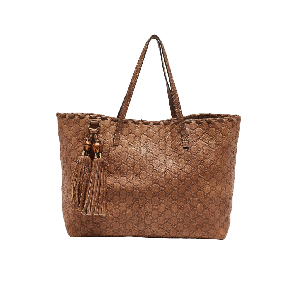 Front view of a Gucci tote bag in medium brown Guccissima leather featuring two large tassels with bamboo accents.