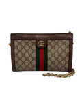 A Gucci GG Supreme canvas clutch bag with brown leather trim, a green and red web stripe, and gold-tone hardware, including a chain strap.