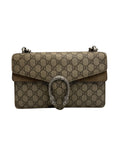 A Gucci Dionysus shoulder bag in brown GG Supreme canvas with a silver-tone metal snake clasp, shown against a neutral gray background.