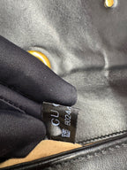 Close-up of gucci marmont with a visible brand tag and black gloves.