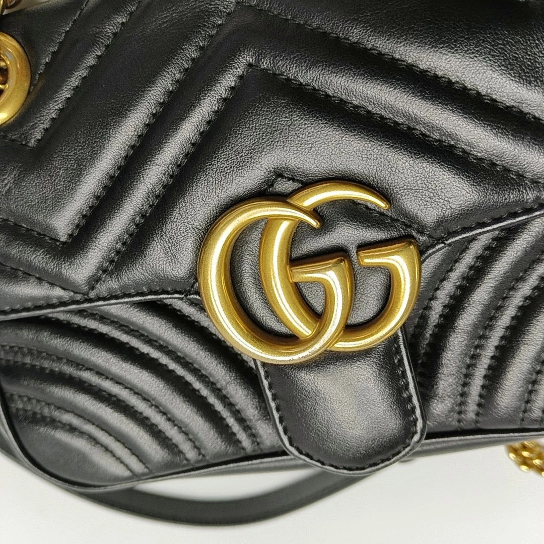 gold hardware of the GG logo on gucci marmont small black leather bag. 