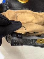 Close-up of a black leather gucci marmont with a visible brand tag and gold hardware.