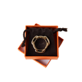 Authentic Hermès Trio scarf ring in gold-tone metal resting on its brown velvet pouch inside the signature Hermès orange box.
