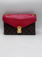 Front view of a Louis Vuitton Double V shoulder bag in Monogram canvas with red leather flap and gold S-lock closure.