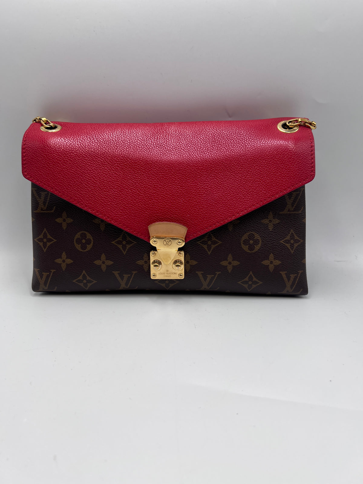 Front view of a Louis Vuitton Double V shoulder bag in Monogram canvas with red leather flap and gold S-lock closure.