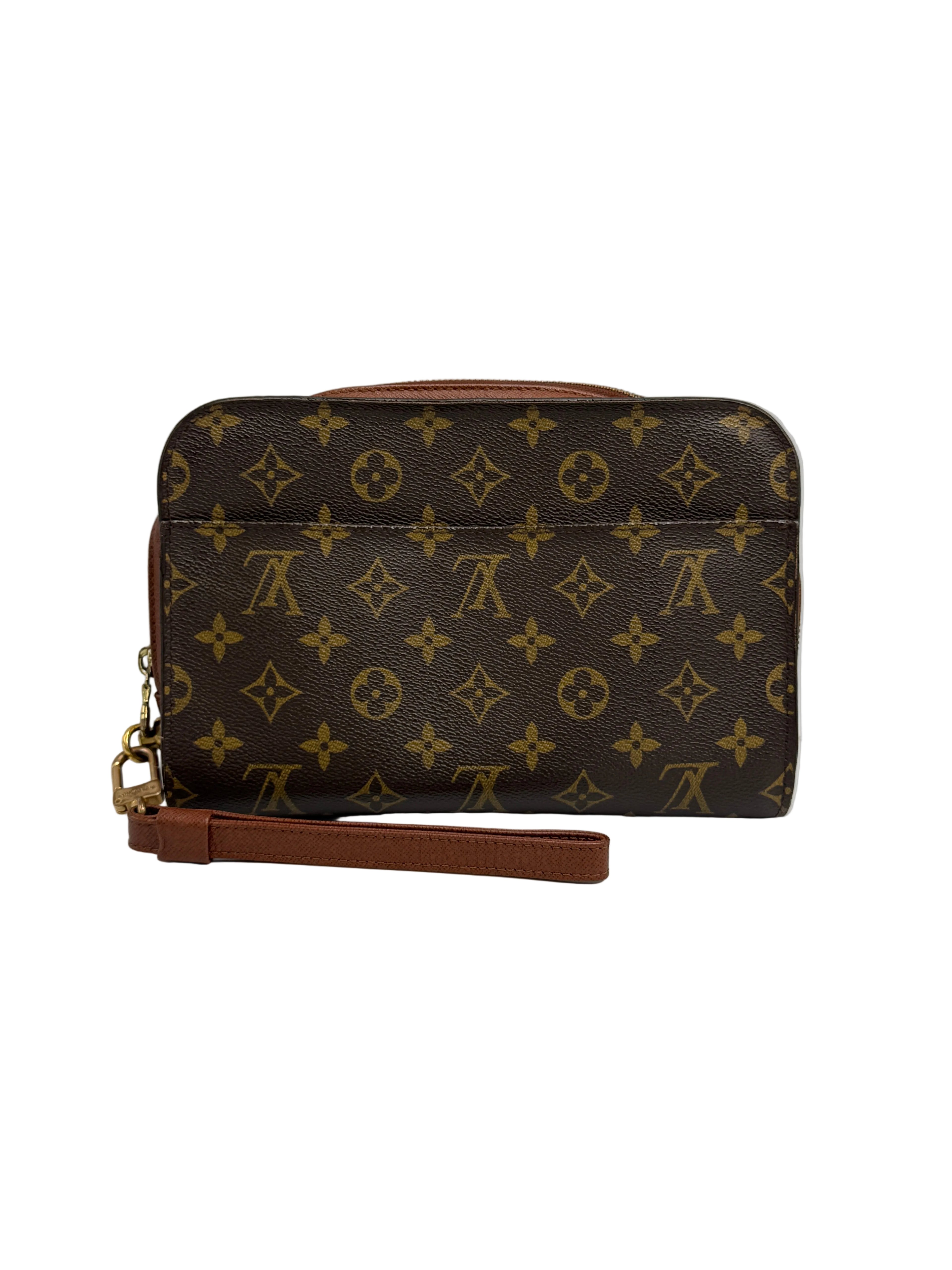 A Louis Vuitton monogram canvas wristlet clutch with a brown leather wrist strap and gold-tone hardware, photographed against a neutral light gray background.