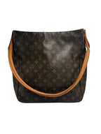 A Louis Vuitton monogram canvas shoulder bag in dark brown with tan leather trim and strap, photographed against a neutral light gray background.