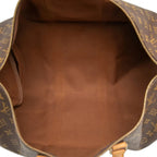 The interior of a Louis Vuitton monogram duffel bag, showing a brown canvas lining and gold-tone zipper details.