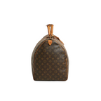 A Louis Vuitton monogram canvas duffel bag with tan leather trim and top handles, photographed against a neutral light gray background.