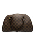 A brown checkered leather handbag with gold-tone hardware and dark brown handles, photographed against a neutral gray background.
