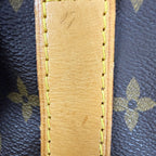 Close-up of a tan leather strap with yellow stitching on a dark brown Louis Vuitton monogram canvas background.