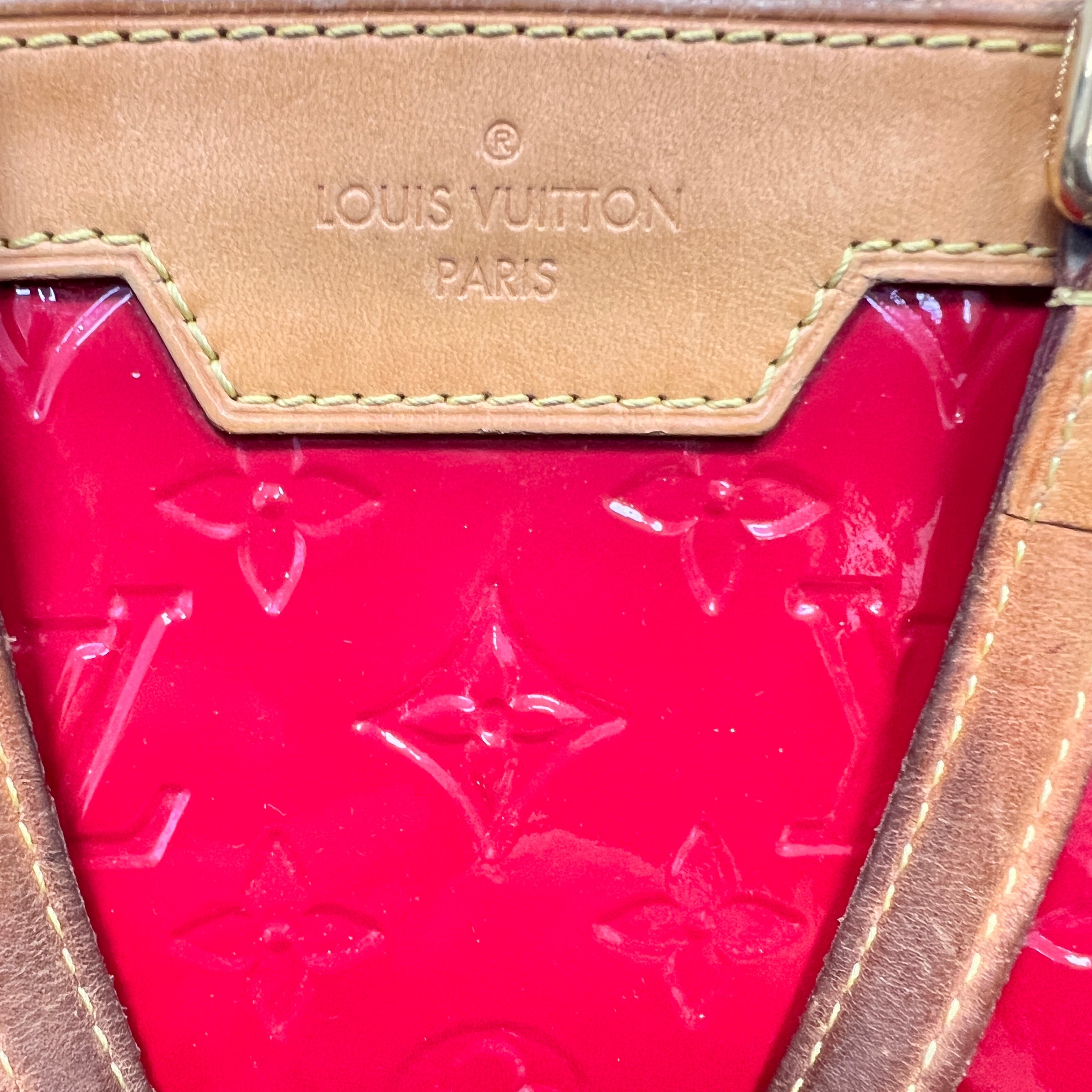 Close-up of a Louis Vuitton handbag showing a bright pink monogram coated canvas body and a tan leather trim with the Louis Vuitton Paris logo embossed on the upper panel.