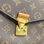 Close-up of the gold-tone S-lock closure on a Louis Vuitton Pochette Métis bag