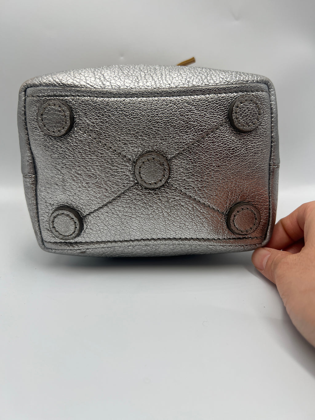 Gray leather wallet with button details held by a hand on a light gray background