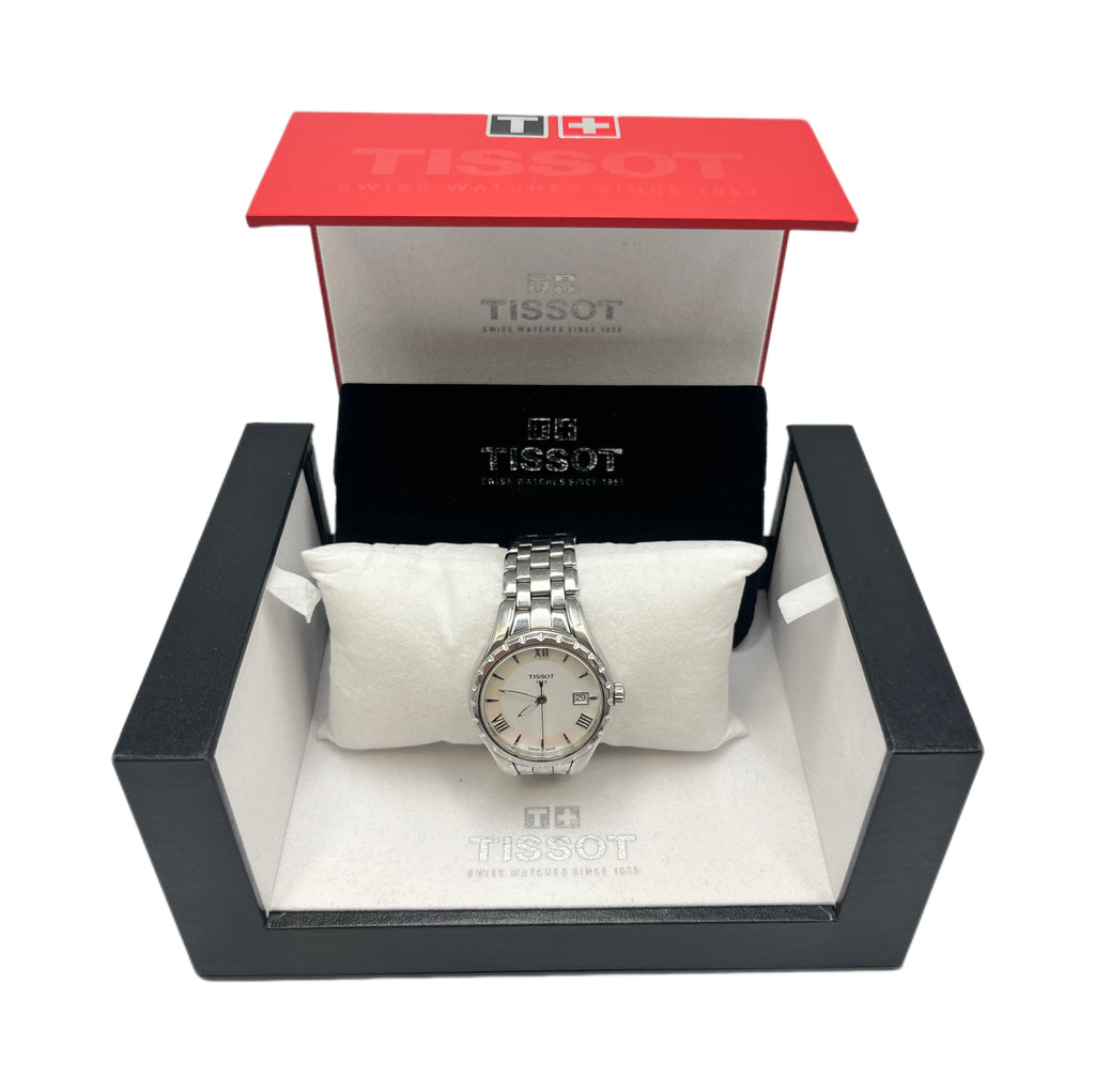 A Tissot stainless steel ladies watch with a white Roman numeral dial, displayed on a white pillow inside its original red and black Tissot presentation box.